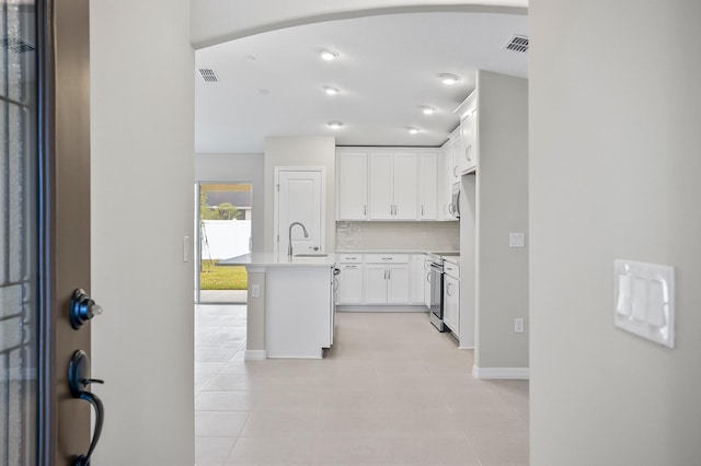 kitchen with sink, a center island with sink, white cabinets, stainless steel electric range oven, and decorative backsplash