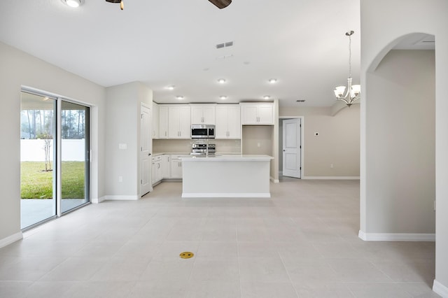 kitchen featuring light tile patterned flooring, a center island, pendant lighting, stainless steel appliances, and white cabinets