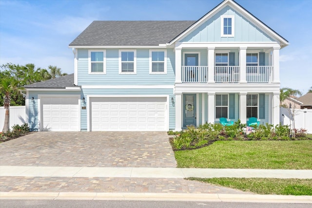 view of front facade featuring a balcony, driveway, fence, covered porch, and a front lawn