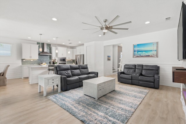 living area featuring a ceiling fan, recessed lighting, light wood-style floors, and visible vents