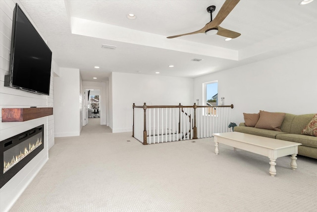living area with ceiling fan, light colored carpet, a glass covered fireplace, and recessed lighting