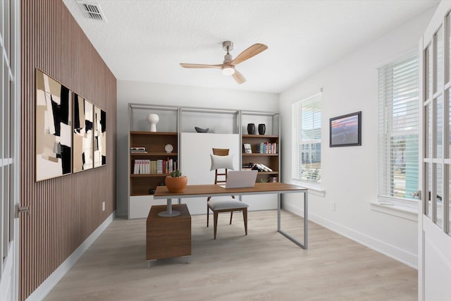 office area featuring light wood finished floors, baseboards, a ceiling fan, and visible vents