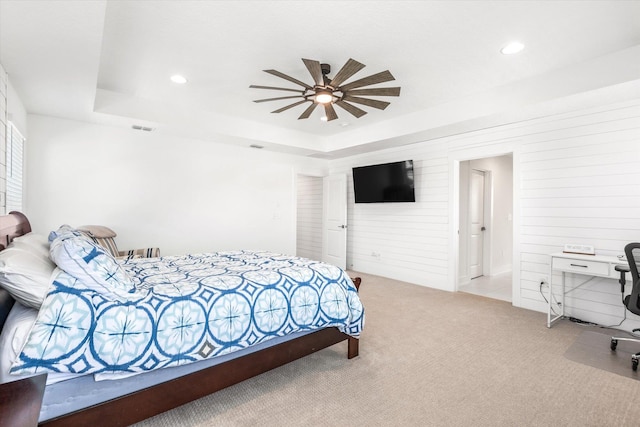 carpeted bedroom featuring a tray ceiling, wooden walls, visible vents, and recessed lighting