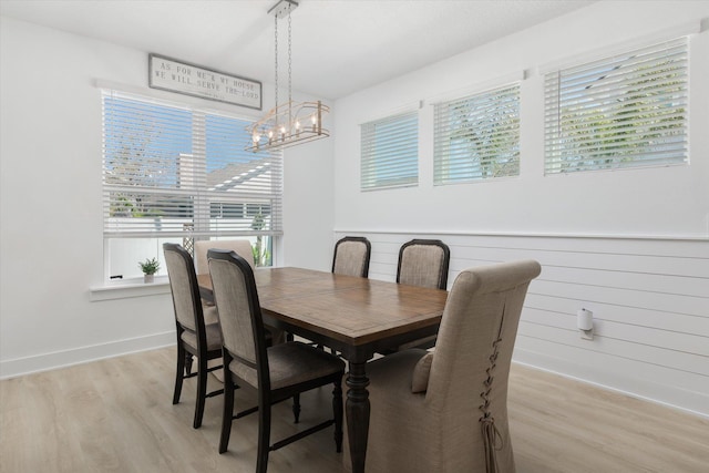 dining space with light wood-type flooring, a healthy amount of sunlight, and a notable chandelier