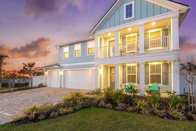 view of front of home featuring covered porch, a garage, board and batten siding, a balcony, and driveway