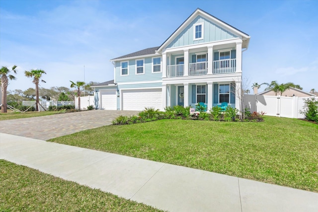 traditional-style home with fence, a front lawn, board and batten siding, a balcony, and driveway