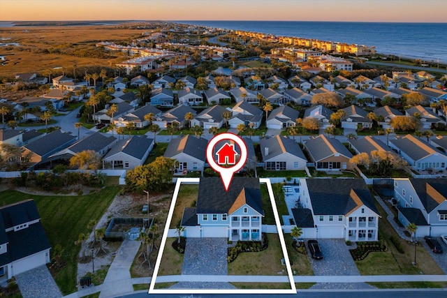 aerial view at dusk featuring a water view and a residential view