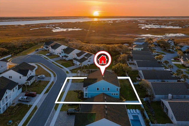 aerial view at dusk featuring a water view and a residential view