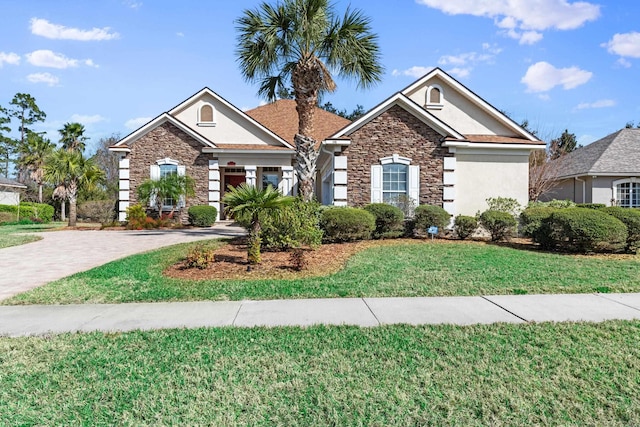 view of front of property with a front lawn, decorative driveway, stone siding, and stucco siding