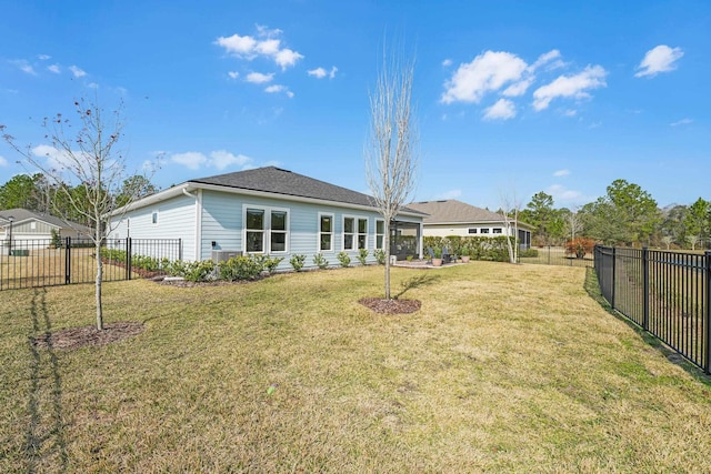 rear view of house featuring a fenced backyard and a lawn