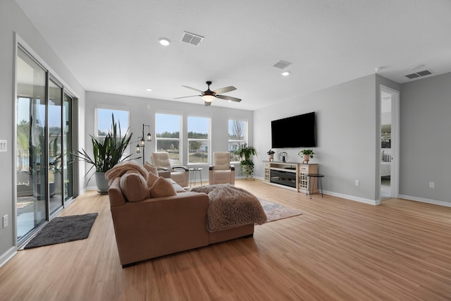 living room with light wood-type flooring, baseboards, and visible vents