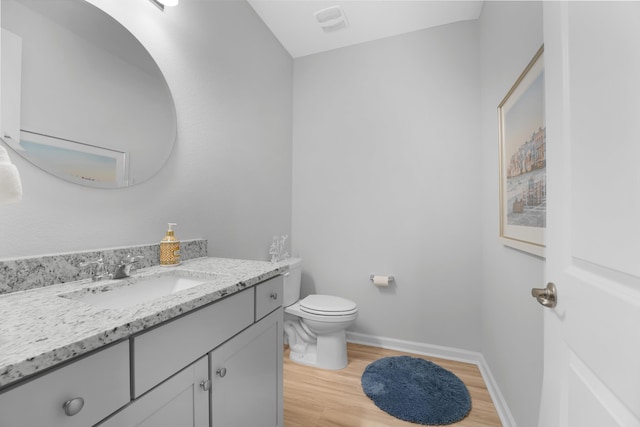 bathroom with toilet, wood finished floors, visible vents, vanity, and baseboards