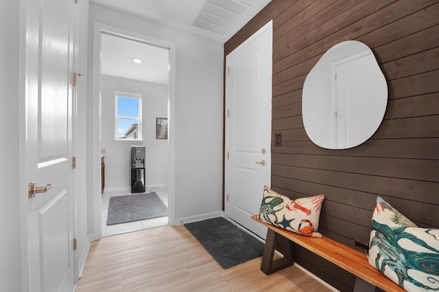 interior space featuring light wood-style flooring, wooden walls, visible vents, and baseboards