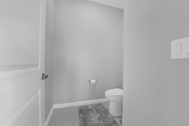 bathroom with toilet, tile patterned flooring, and baseboards