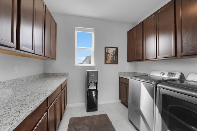 clothes washing area featuring independent washer and dryer, cabinet space, light tile patterned flooring, and baseboards