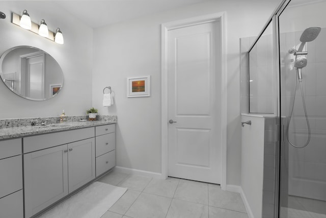 full bath featuring tiled shower, vanity, baseboards, and tile patterned floors