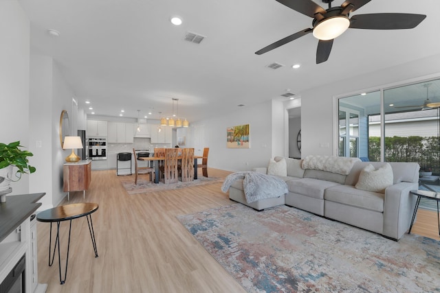 living room featuring light wood finished floors, visible vents, and recessed lighting