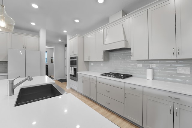 kitchen with tasteful backsplash, stainless steel appliances, light countertops, and a sink
