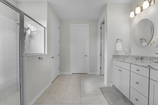 bathroom with baseboards, tiled shower, vanity, and tile patterned floors