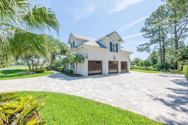 248 Marshside Dr, Saint Augustine, FL 32080 - view of side of property with an attached garage, stucco siding, decorative driveway, and a lawn