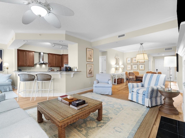 living room with a ceiling fan, baseboards, visible vents, and crown molding