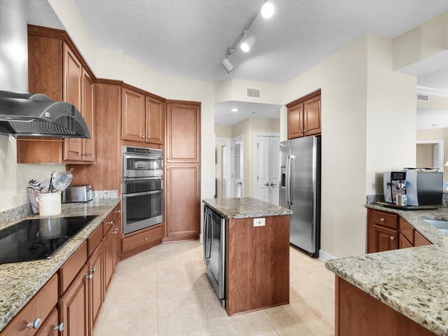 kitchen featuring a kitchen island, visible vents, appliances with stainless steel finishes, light stone countertops, and wall chimney exhaust hood