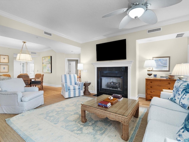 living area with ornamental molding, wood finished floors, and visible vents