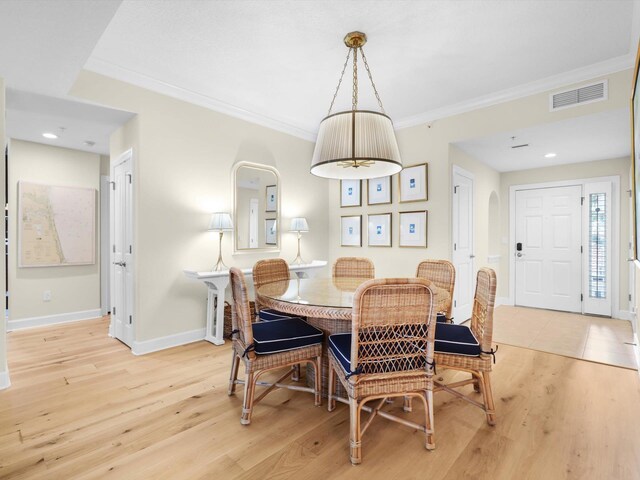 dining room featuring light wood-type flooring, visible vents, crown molding, and baseboards