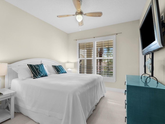 bedroom featuring a ceiling fan, light carpet, and baseboards