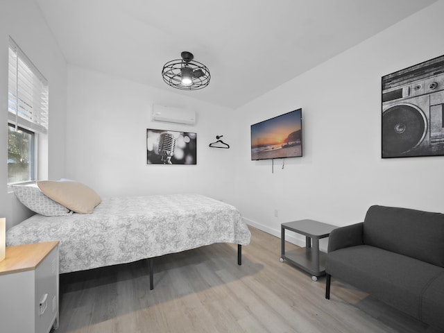 bedroom with a wall mounted AC and hardwood / wood-style floors