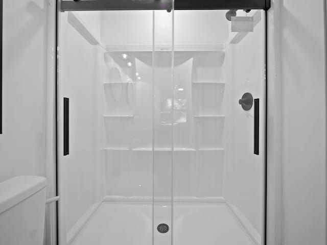 bathroom with toilet and a shower with shower door