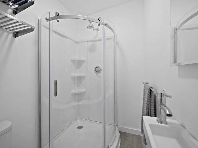 bathroom featuring hardwood / wood-style flooring, toilet, and an enclosed shower