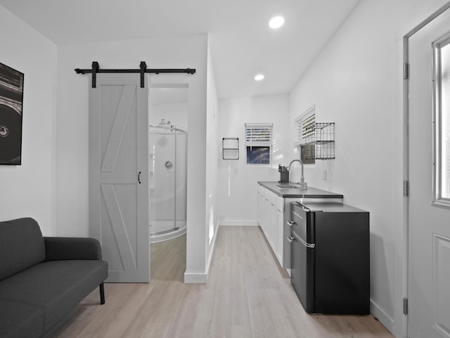 kitchen featuring sink, refrigerator, a barn door, light hardwood / wood-style floors, and white cabinets