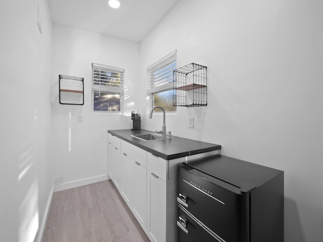 bar with light wood-type flooring, refrigerator, sink, and white cabinets