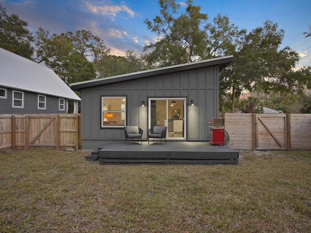 back house at dusk featuring a yard and a deck