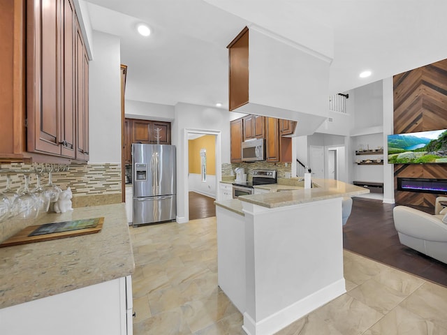 306 Marsh Point Cir, Saint Augustine, FL 32080 - kitchen with stainless steel appliances, light stone counters, decorative backsplash, a peninsula, and recessed lighting