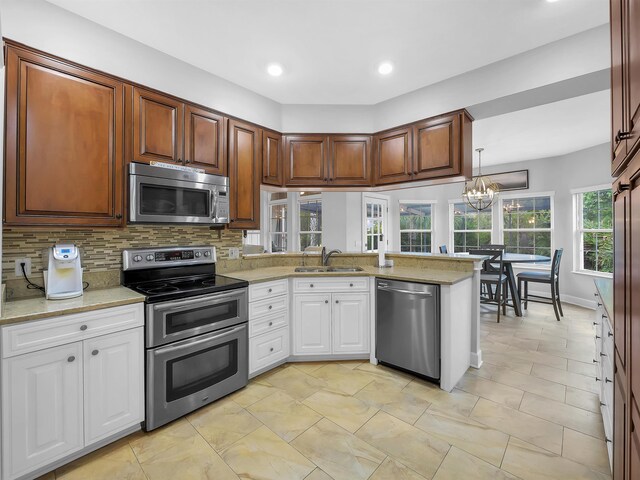 306 Marsh Point Cir, Saint Augustine, FL 32080 - kitchen featuring stainless steel appliances, a peninsula, decorative backsplash, white cabinetry, and a chandelier