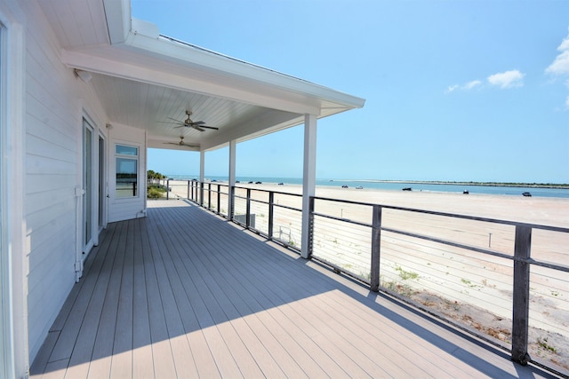 wooden deck featuring a water view, a view of the beach, and ceiling fan