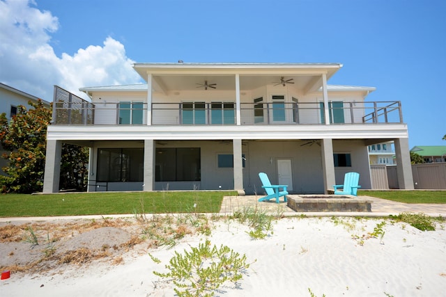 rear view of property featuring a balcony, an outdoor fire pit, a patio, ceiling fan, and a lawn