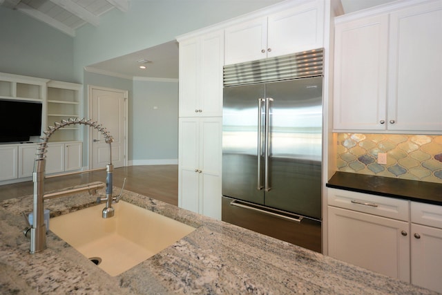 kitchen featuring sink, white cabinetry, light stone countertops, and stainless steel built in refrigerator