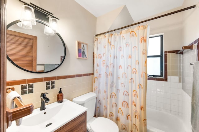 full bath featuring tile walls, a wainscoted wall, toilet, shower / tub combo, and vanity