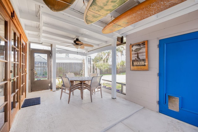 sunroom / solarium featuring beamed ceiling and ceiling fan