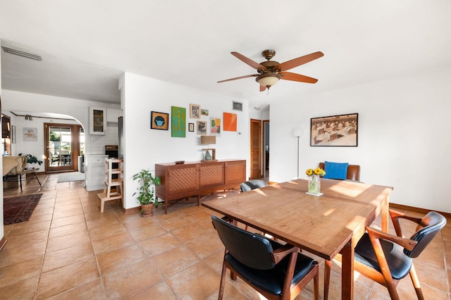 dining area with arched walkways, visible vents, baseboards, and a ceiling fan