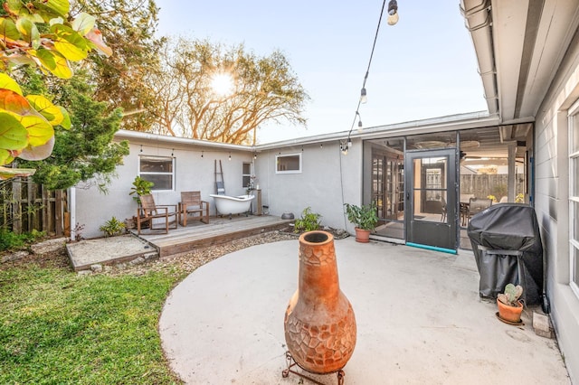 rear view of house with a patio area, fence, a sunroom, and stucco siding