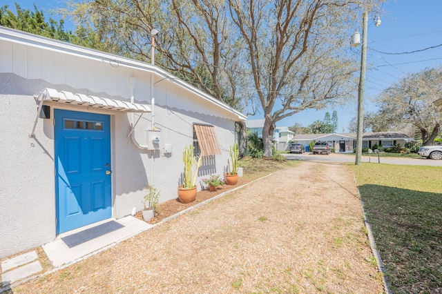 property entrance with stucco siding and a yard