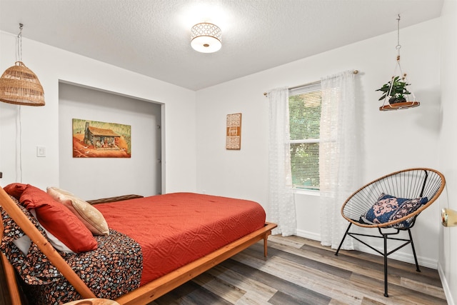 bedroom with hardwood / wood-style floors and a textured ceiling