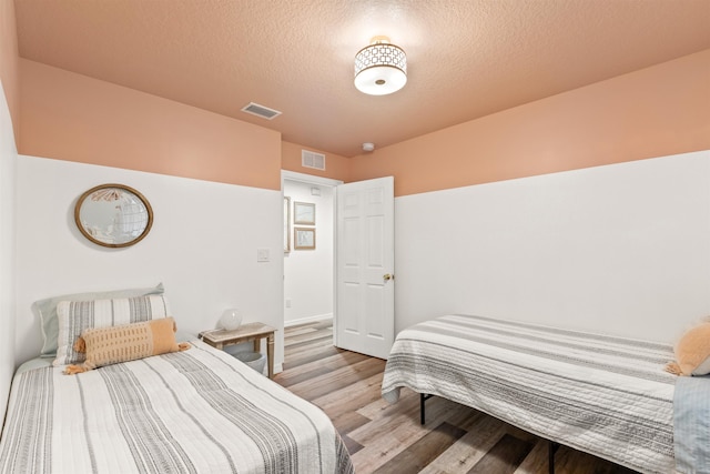 bedroom featuring light hardwood / wood-style flooring and a textured ceiling