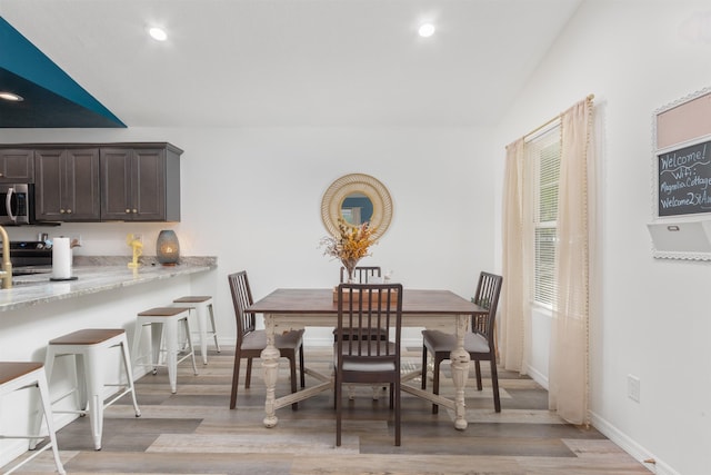 dining room with light hardwood / wood-style flooring and vaulted ceiling