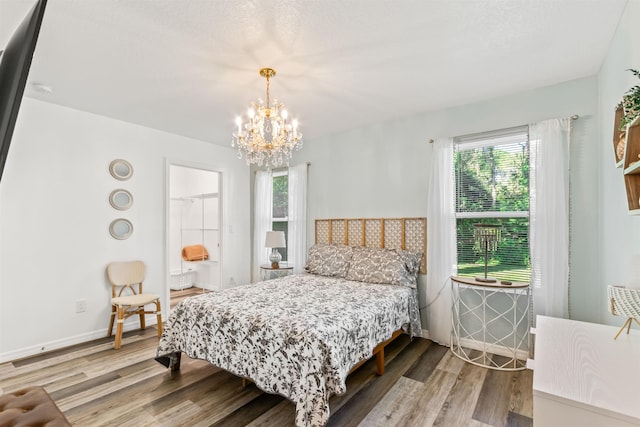 bedroom featuring multiple windows, wood-type flooring, and a notable chandelier