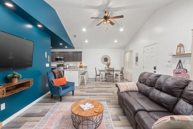 living room featuring sink, high vaulted ceiling, ceiling fan, and light wood-type flooring